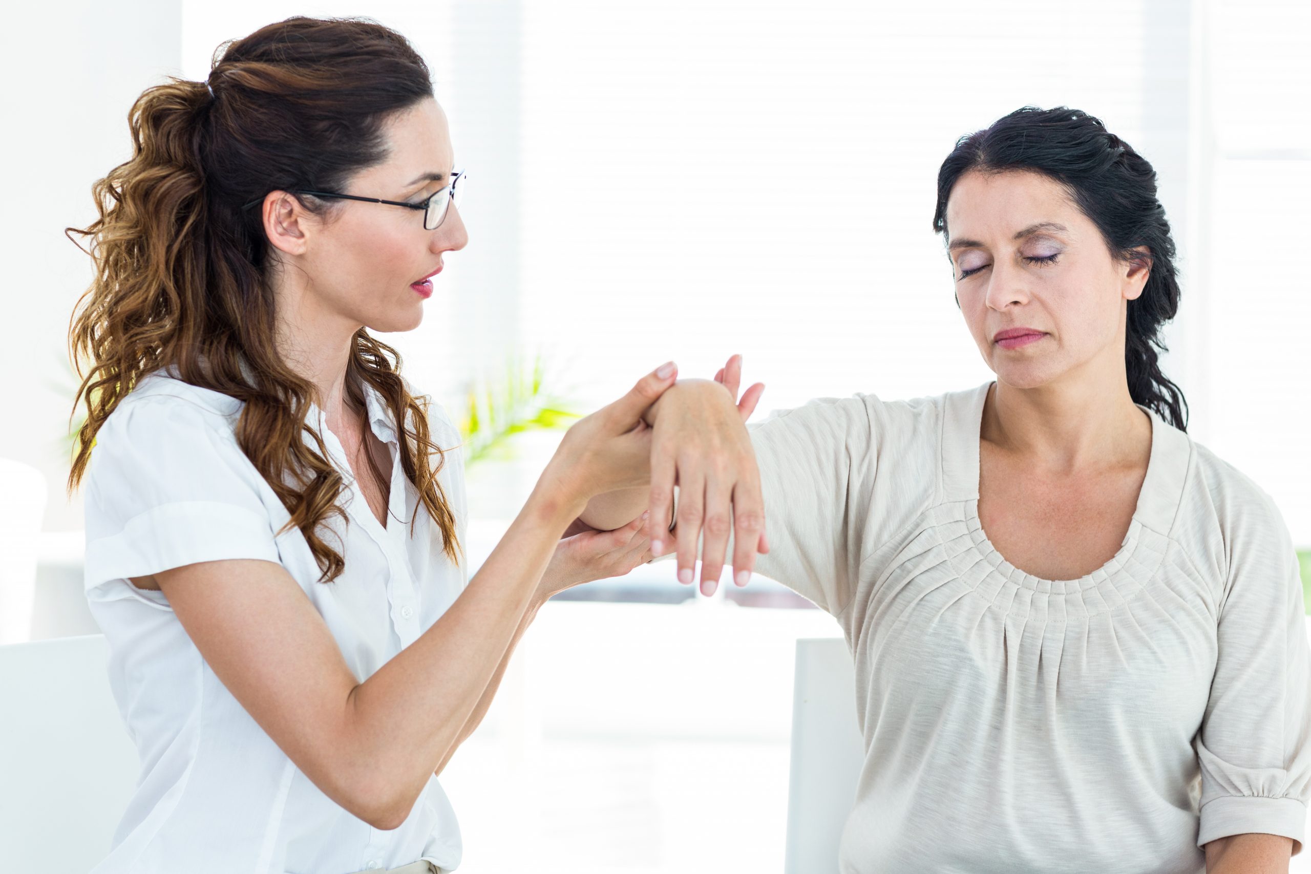 Therapist holding her patients arm on white background
